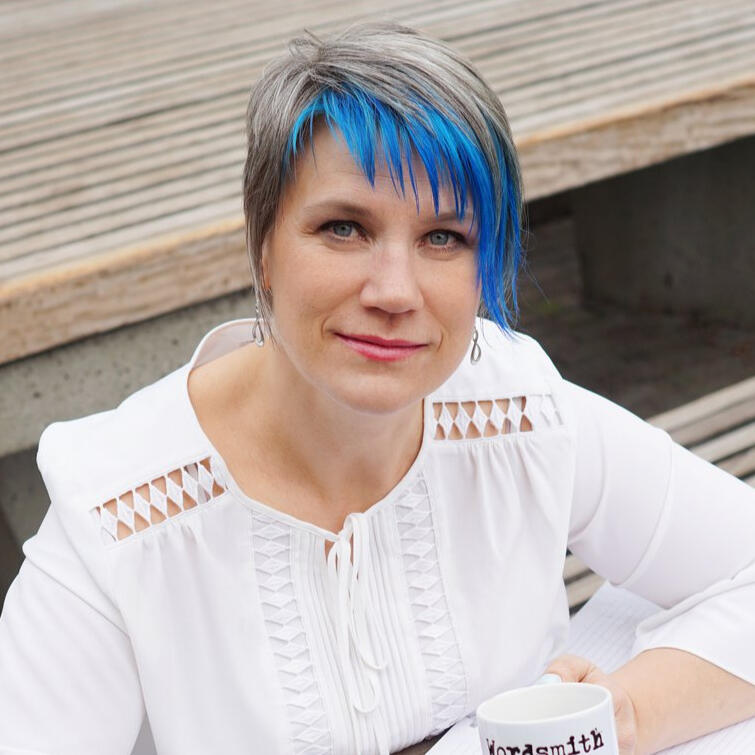 Andrea_York_spiritual_direction_for_your_spiritual_journey woman with blue hair wearing a white blouse sitting at a table, looking at the camera